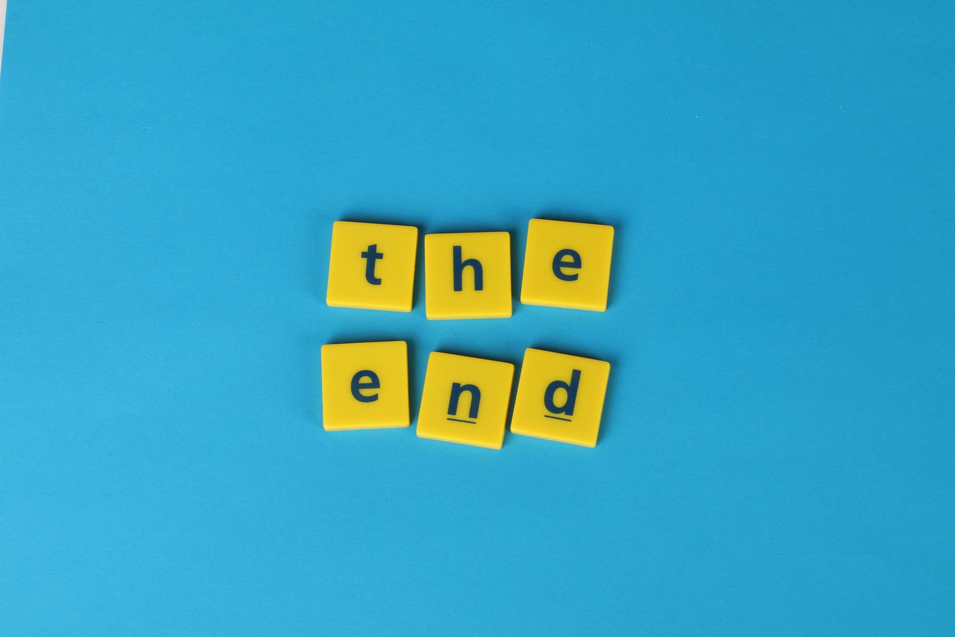 Yellow letter tiles spelling 'the end' on a vibrant blue background create a striking visual.