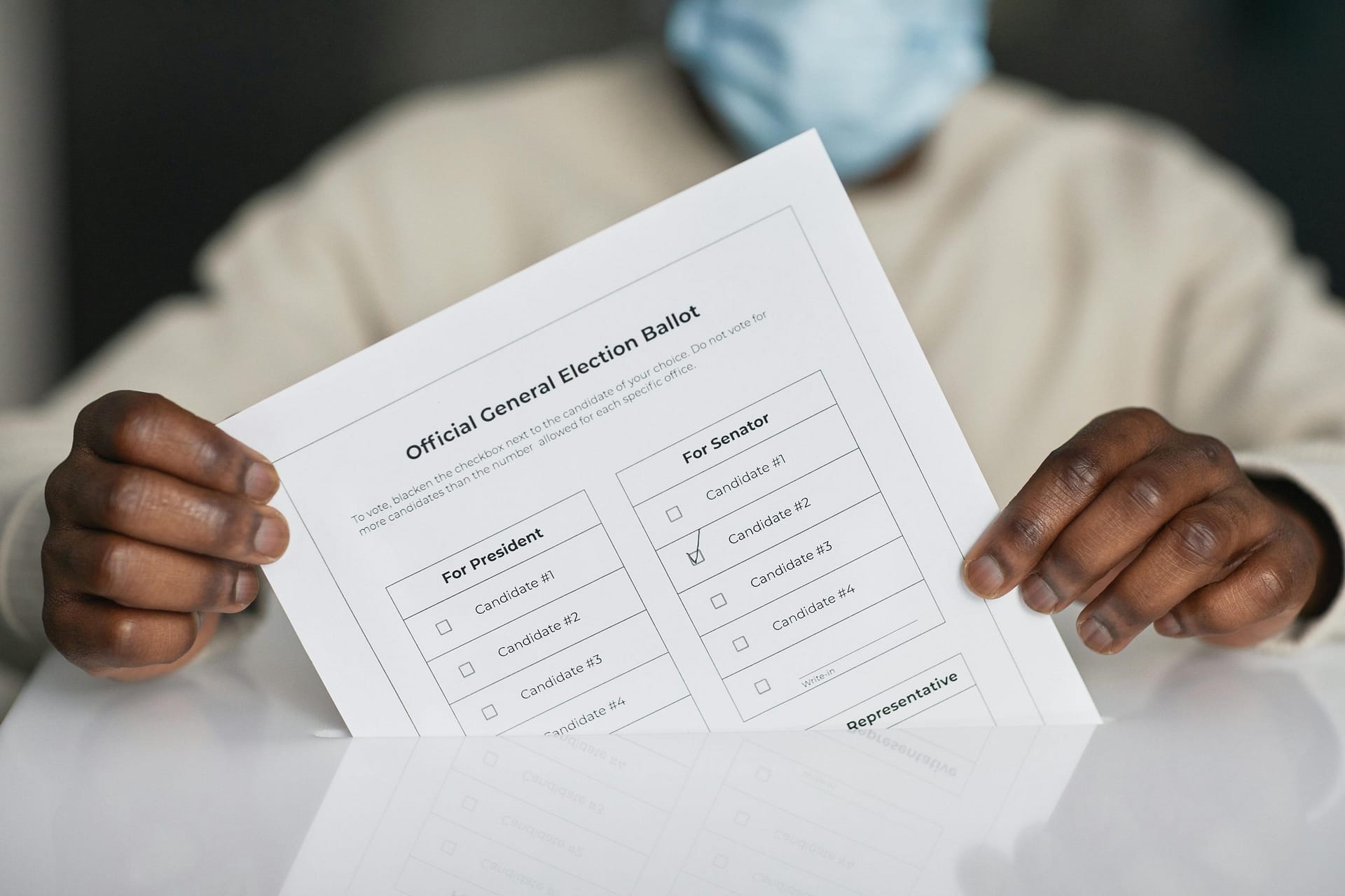A person wearing a face mask holds an official general election ballot.