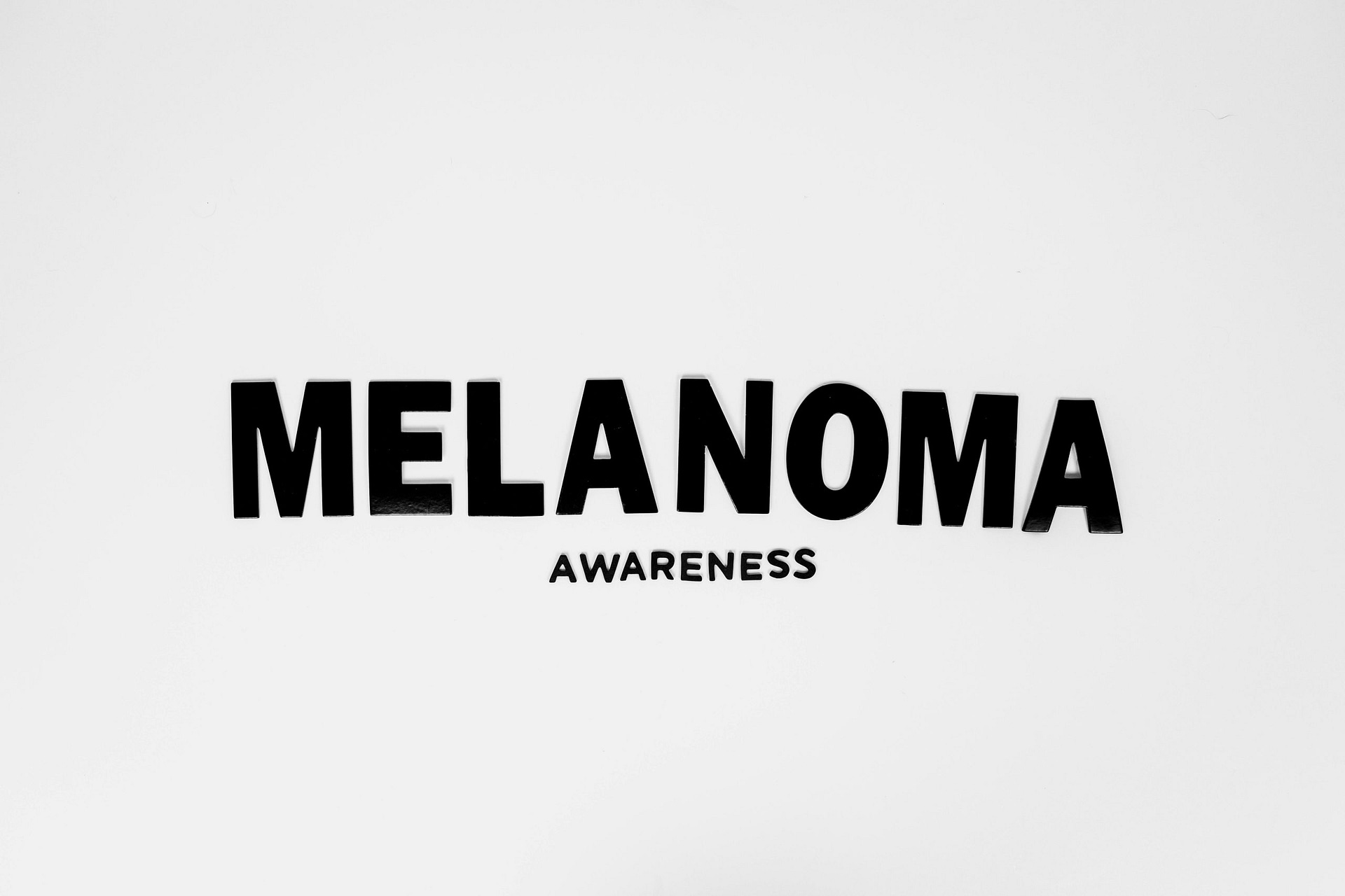 Black text 'Melanoma Awareness' on a white surface emphasizing skin cancer awareness.