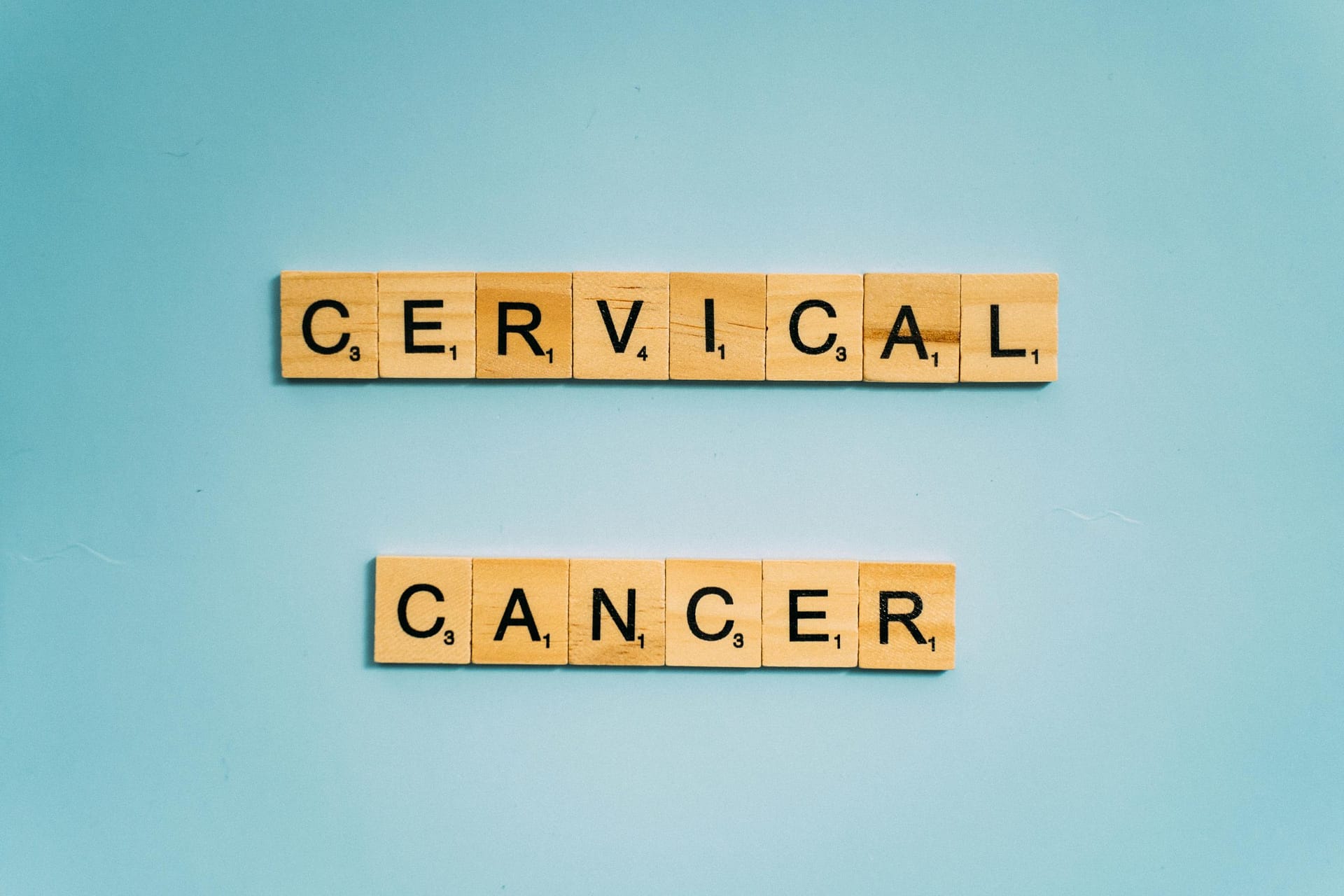 Scrabble tiles spelling 'Cervical Cancer' on a light blue background for awareness.